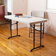 a white table and chair in a room with hard wood flooring on the ground