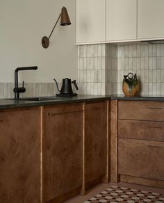 a kitchen with wooden cabinets and black counter tops, an old fashioned tea kettle on the sink