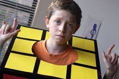 a young boy wearing a rubik cube costume with his hands in front of him