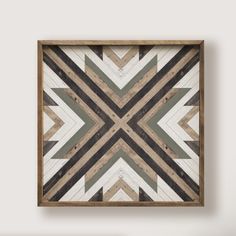 a wooden frame hanging on the wall with an abstract geometric design in grey and white