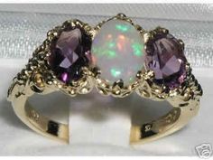 This ring is made from Solid 750 18ct 18K Yellow Gold with Natural Semi-precious Opal & Amethysts.*Total gemstone weight :Opal 0.75ct, Amethyst  1.5ctOne Center 8x6 mm (0.32" x 0.24") Opal and two 7x5 mm (0.28" x 0.20") Beautiful Vibrant Amethysts oval cut set in a Solid Yellow Gold Antique / Victorian style prong setting. This ring has a good solid feel, a nice weight and a good thick shank.*Total Height 5mm, Width 16mm, Length 11mm Solid English 18K Gold - on the inside of the shank there Trilogy Ring, Carved Ring, Precious Opal, Australian Opal, Natural Opal, Anniversary Ring, Amethyst Ring, Pink Tourmaline, Victorian Fashion