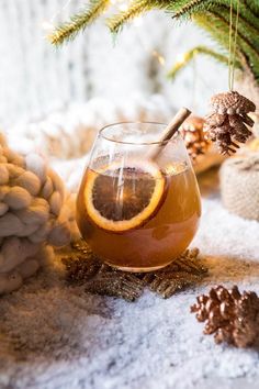 a glass filled with liquid sitting on top of a table next to pine cones and branches