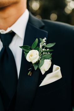 a man wearing a black suit and white flower boutonniere