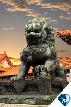 a statue of a lion in front of a building with an orange sky behind it