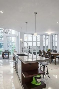 an open kitchen and dining room area with white tile flooring, large windows, and chandelier hanging from the ceiling