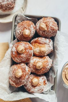 powdered sugar donuts with peanut butter on top in a basket next to coffee