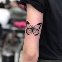 a black and white butterfly tattoo on the arm