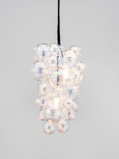 a chandelier hanging from a black cord in the shape of bubble balls on a gray background