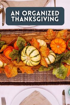 an organized thanksgiving table setting with pumpkins, gourds and leaves on it