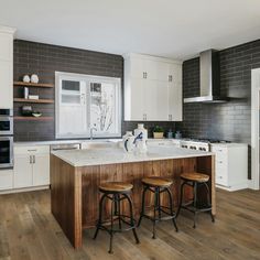 a kitchen with white cabinets and wooden stools next to an island in the middle