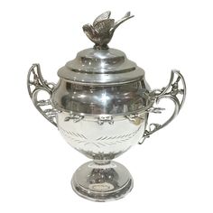 a silver vase with a bird on top