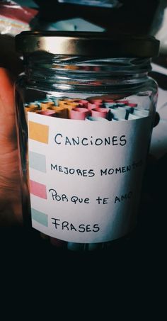 a jar filled with lots of colorful candies next to a person's hand