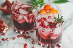 two glasses filled with pomegranate and garnished with rosemary