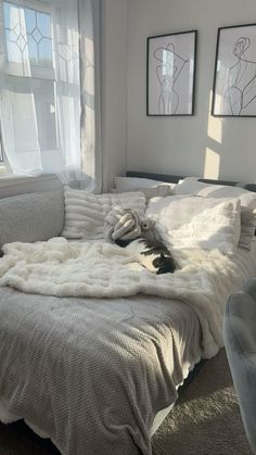 a bed with blankets and pillows on top of it in front of two pictures hanging on the wall