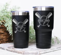 two black tumblers with baseballs and bats on them sitting next to a potted plant