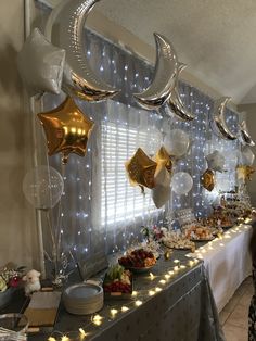 a long table with balloons, plates and desserts on it