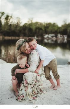 a woman and two children hugging each other on the beach