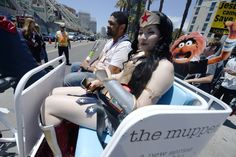 a woman riding on the back of a motorcycle next to a man in a costume