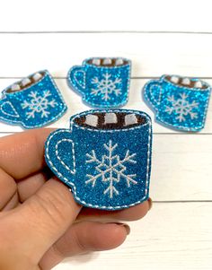 someone is holding some small blue mugs with snowflakes on them