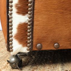 a close up of a cowhide chair with metal studs on the legs and back