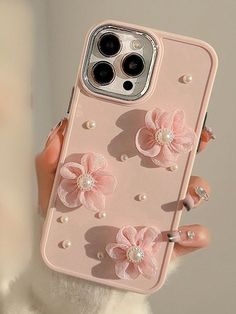 a woman holding an iphone case with flowers and pearls on the back in her hand