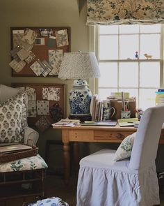 a desk with a chair, lamp and pictures on the wall in front of it