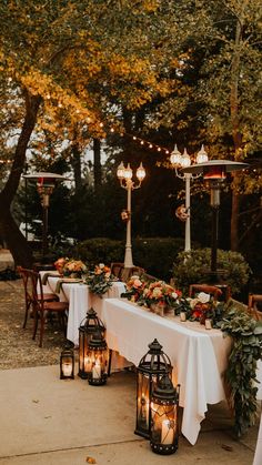 a long table with candles and flowers on it is set up for an outdoor dinner