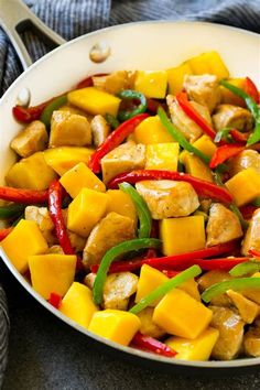 a pan filled with chicken and peppers on top of a table