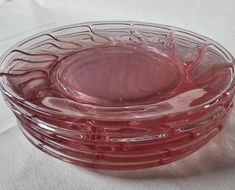 a red glass bowl sitting on top of a white cloth covered tablecloth with the lid down