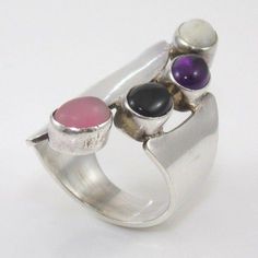 Native American Charlie O Sterling Silver Large Gemstone Statement Ring Size 10 Us Ring Size 10 Uk Ring Size T1/2 Gram Weight 14.6 Size Of Ring Face (North To South By East To West) In Millimeters 41 X 11 Main Stone Type Multi Gemstone Length And Width Of Main Stone In Millimeters 8 X 6 Hallmarked Yes Tested Yes Condition Issues Other Than Ordinary And Normal Use Marks N/A Inventory Number Sfa-230-Aa01 Please Contact Us With Any Questions. We Love To Hear From Shoppers. Modern Sterling Silver Rings With Stones, Modern Multi-stone Sterling Silver Gemstones, Modern Multi-stone Gemstones In Sterling Silver, Modern Silver Rings With Natural Stones, Modern Multi-stone Silver Gemstones, Silver Multi-stone Moonstone Ring In Sterling Silver, Modern Silver Multi-stone Rings, Silver Fusion Rings With Gemstone Accents, Silver Multi-stone Moonstone Ring