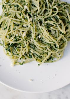 a white plate topped with pasta covered in pesto