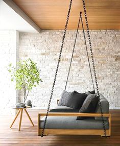 a living room with a gray couch and black pillows on the swing bed in front of a white brick wall