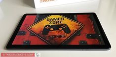 a tablet with a warning sign on it and a video game controller in front of it