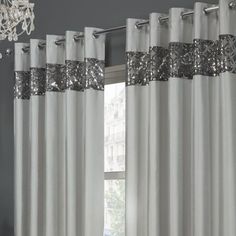 white curtains with silver sequins on them in front of a chandelier