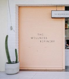 the entrance to a restaurant with a cactus in front of it and an open door that says, the wellness refinery