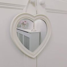 a heart shaped mirror hanging on the side of a door with a vase in it