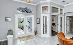 a living room filled with lots of furniture and white trim on the walls, doors and windows