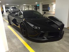 a black sports car is parked in a parking garage next to other cars on the street