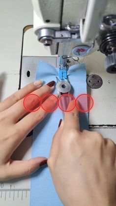 a person using a sewing machine to sew on some blue material with red circles