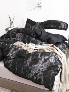 an unmade bed with black and white marbled comforter on it's side