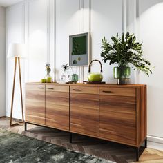 a large wooden cabinet with plants and vases on it in a white living room