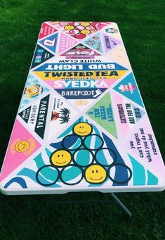 a table that is sitting in the grass with some stickers on it and smiling faces