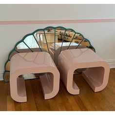 two pink stools sitting on top of a wooden floor next to a large mirror