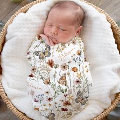 a baby is sleeping in a basket with flowers on the bottom and white blanket around it