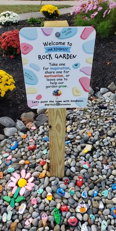 a rock garden sign surrounded by flowers and rocks