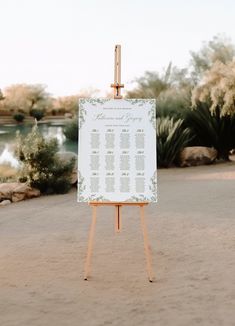 an easel with a wedding seating plan on it in the middle of a desert