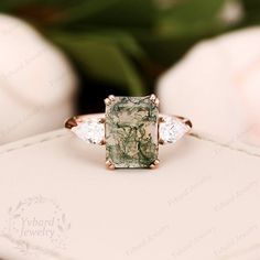 a green and white ring sitting on top of a table next to some pink flowers