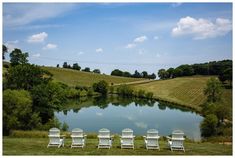 four lawn chairs sitting in front of a lake