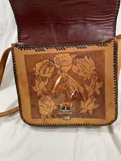 "Measurements are 10\"2 wide, 9\"5 high, 3\"4 deep with one 34\" shoulder strap with a 13\" drop. On the interior there is one main compartment, leather lined interior with a front flap closure with tooled horse on front and back. The leather on this beauty is thick and strong with no tears, light water marks and has flowers and name Bert on the front flap. Bag comes with silver tone hardware, thick leather, black thick stitch and the shoulder strap is strong. Bag is vintage and in good conditio Western Style Hand Tooled Brown Shoulder Bag, Western Style Brown Hand Tooled Shoulder Bag, Western Style Rectangular Shoulder Bag For Travel, Western Style Hand Tooled Brown Bag, Western Style Rectangular Bag With Adjustable Strap, Western Hand Tooled Travel Bag, Western Style Hand Tooled Shoulder Bag For Travel, Western Style Hand-tooled Travel Bag, Western Leather Crossbody Shoulder Bag