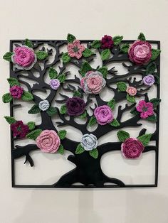 a tree made out of crocheted flowers on a white wall with black frame